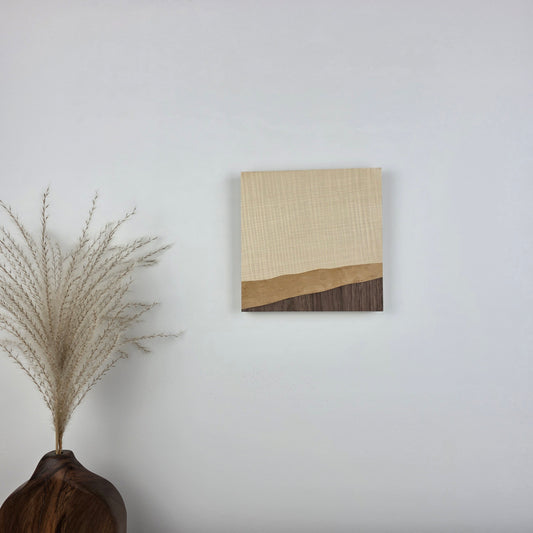 Wood Grain 001 is an original wooden art piece on a white wall with a vase and dried plant in the foreground. Jennifer Mourato Art Collection