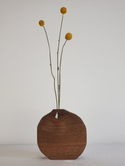 Wooden bud vase with dried flowers on a white wall
