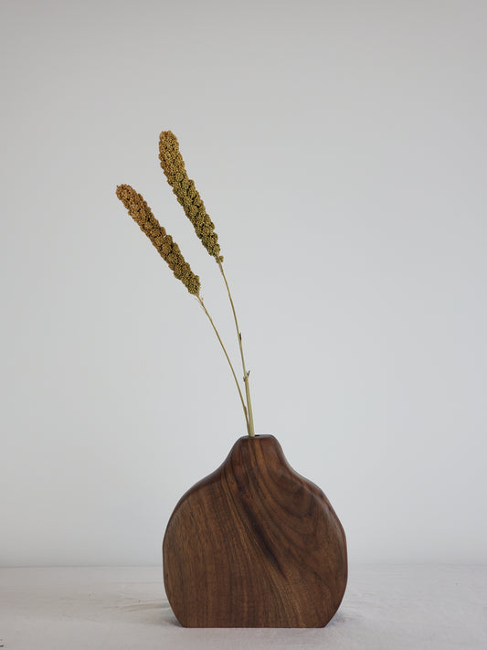 Wooden bud vase with dried plant on a white background