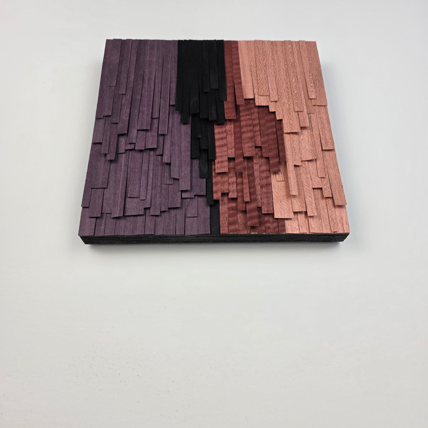 Wooden wall art with vertical slats in black, and purple on a white background