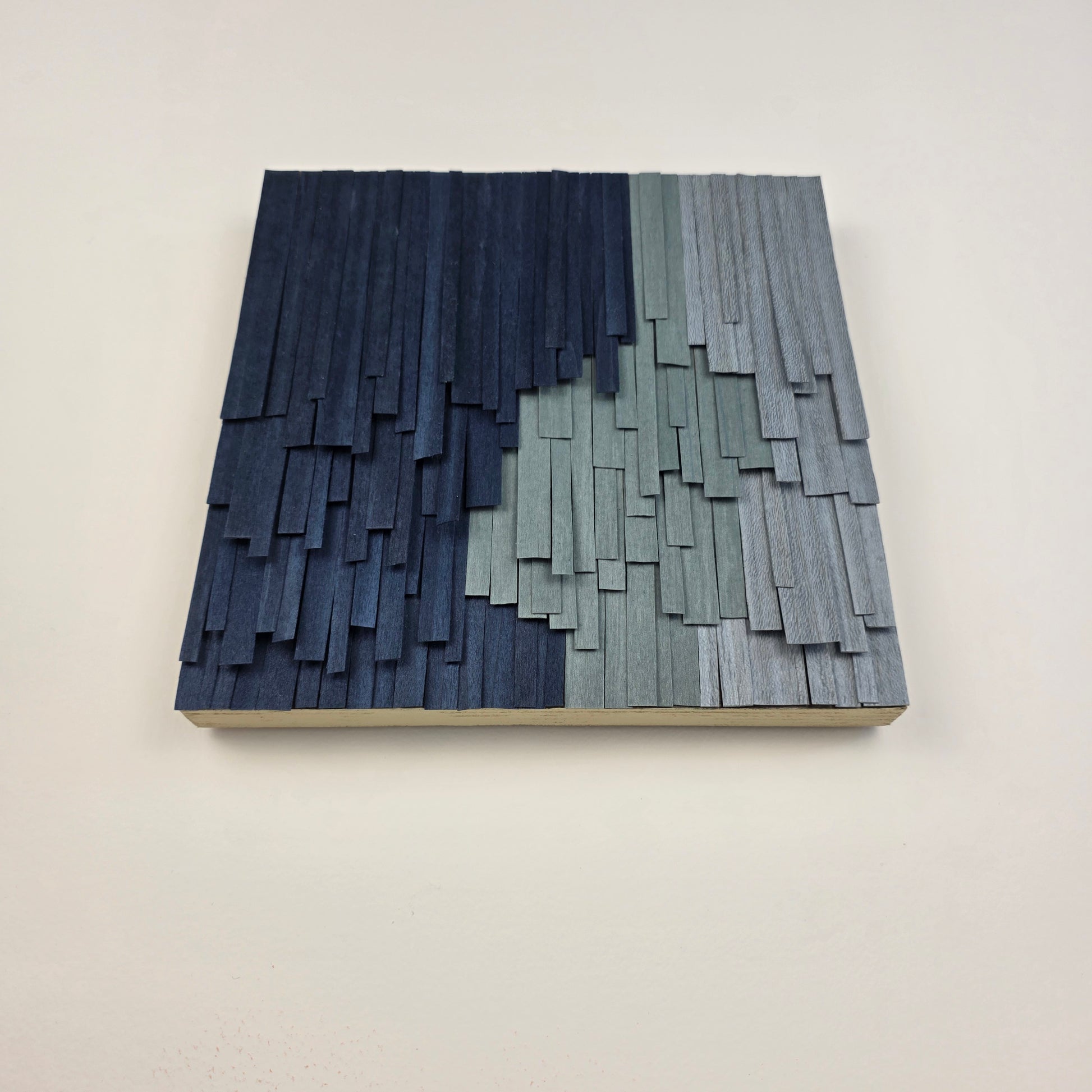Wooden wall art with a geometric pattern on a plain background