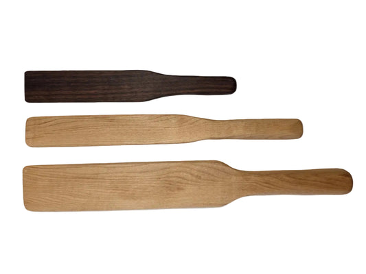 Three wooden spurtles of different colors on a white background