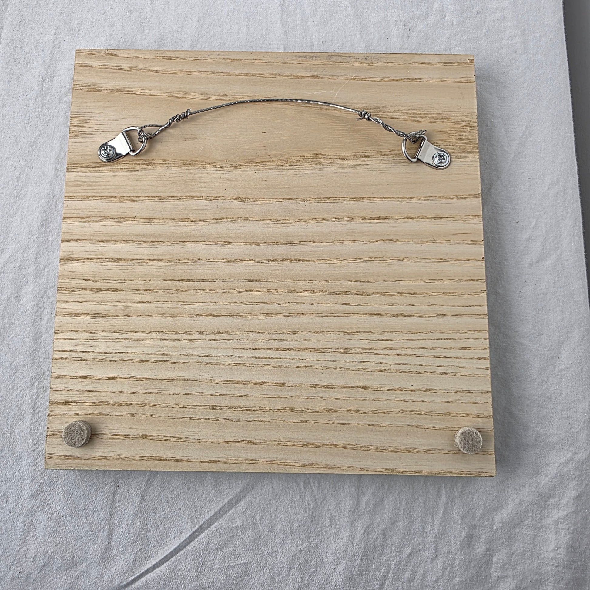 Wooden plaque with metal clips on a gray surface